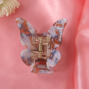 Detail of butterfly claw clip with blue marble pattern on pink satin background