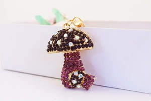 Macro shot of purple rhinestone mushroom keychain with gold plating on a white box