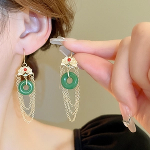 Boucles d'oreilles chinoises en jade avec pompons dorés portées par un mannequin de profil