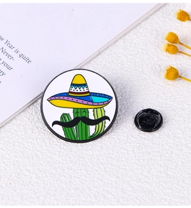 Detail of cartoon cactus enamel pin with sombrero on a white textured desk background