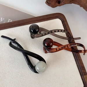 Detail shot of three vintage twisted claw clips with round ball accents in earthy tones