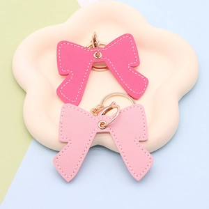 Pink and deep pink bow leather keychains with golden hardware on a flower tray
