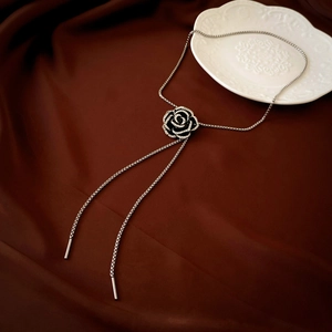 Close-up of a vintage black camellia pendant featuring rhinestones on a silver chain