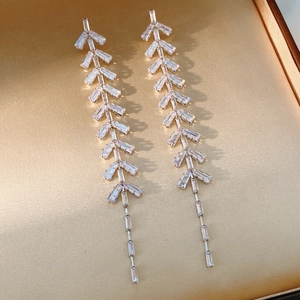 Close-up of silver tassel earrings with baguette-cut zircon leaves in a jewelry box