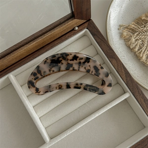 Detail of leopard print acetate hair claw with Creation France text in a wooden jewelry box