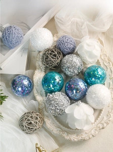 Macro shot of assorted Christmas baubles with glitter, sequins and knit textures on a tray