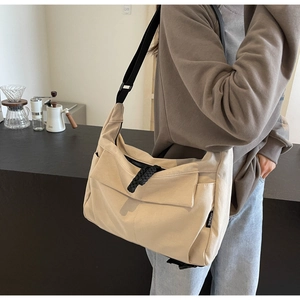 Detail of beige canvas tote bag showing the black brand label and fabric texture