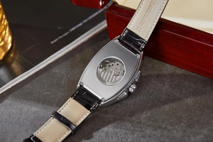 Detail of tonneau mechanical watch back with stainless steel case and leather strap