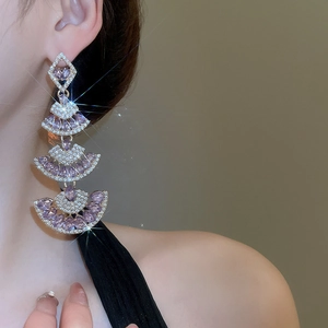 Detail of elegant fan-shaped drop earrings with purple gems and pavé diamond stones