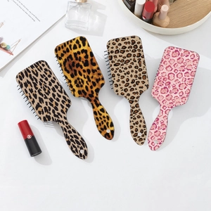 Flat lay of leopard print hair brushes with air cushions on white marble surface