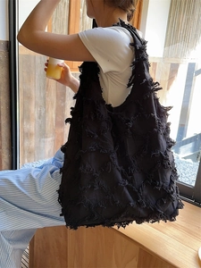 Frayed oversized black canvas tote bag with quilted diamond pattern and fringe detail