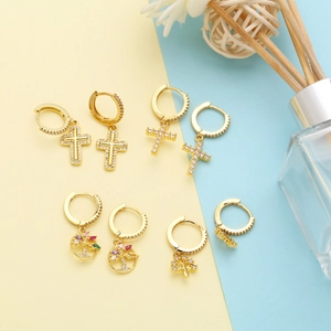 Close-up of gold cross earrings and tree of life pendants with colorful zircons