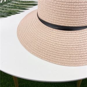 Detail of pink woven straw sun hat showing dense spiral texture and black ribbon trim