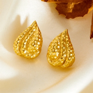 Gold-plated teardrop earrings with dotted hammer texture on premium silk background