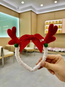 Detail of plush Christmas headband with red reindeer antlers and large decorative bow