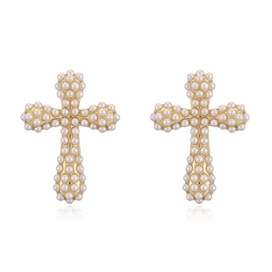 Gros plan de boucles d'oreilles croix dorées avec perles d'imitation sur fond blanc