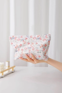 Close-up of floral jacquard cotton makeup bag with brand label on a soft hand