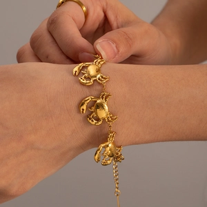 Close-up of golden stainless steel bracelet with three detailed 3D crab charms on wrist