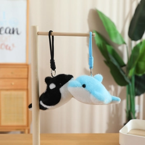 Detail of plush orca and dolphin charms with soft faux fur texture and woven cords