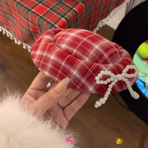 Detail of red plaid hat clip with white pearl beaded bow accessory for women