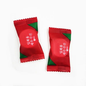 Portable disposable compressed facial towel in red candy packaging for travel use