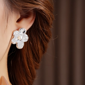 Detailed close-up of a silver flower earring featuring a central pearl and hammered texture