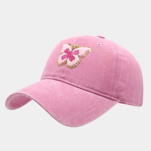 Détail d'une casquette rose délavée avec papillon brodé et finitions en fil doré