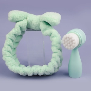 Detail of mint green plush bow headband and manual facial cleansing brush set