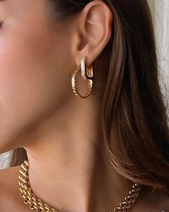 Detail of model wearing gold twisted hoop earrings and small rectangular zircon studs