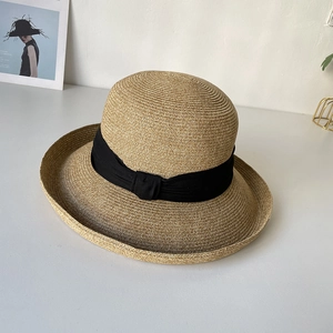 Close-up of elegant wide-brim straw hat featuring detailed weave and black ribbon bow