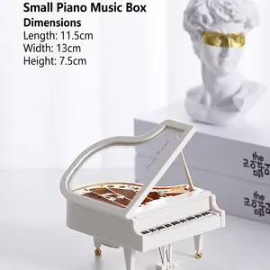 Detail of white mini piano music box with transparent lid and gold mechanical parts