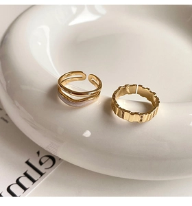 Close-up of dual-layer gold rings with white inlay and vintage mechanical texture