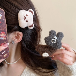 Close-up of plush bear hair clips in cream, brown and grey with soft faux fur texture