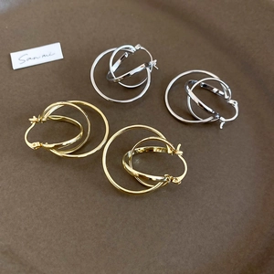 Detail view of gold and silver metallic geometric layered hoop earrings on a ceramic dish