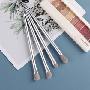 Macro detail of 4-piece silver eyeshadow brush set with soft bristles on blue background