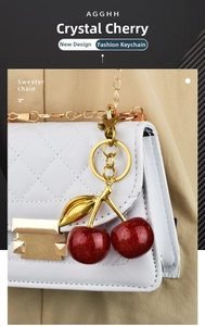 Detail of red glitter cherry pendant with gold leaf on a white quilted bag