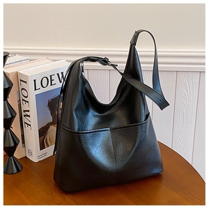 Détail d'un grand sac cabas en cuir noir minimaliste avec couture sur une table en bois