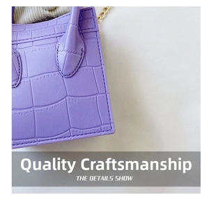 Macro shot of purple crocodile embossed leather handbag with gold chain detail