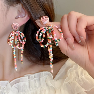 Close-up of handmade floral tassel earrings with pink roses and colorful beaded loops