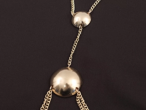 Macro view of gold metal chain necklace featuring polished hemispherical accents and fine links