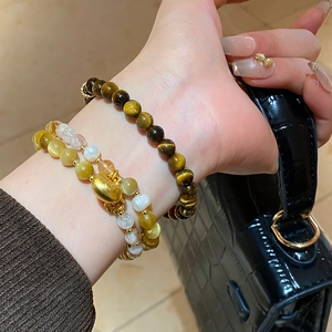 Détail des bracelets en perles d'oeil de tigre avec un pendentif porte-bonheur doré élégant
