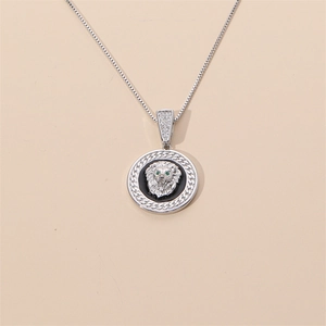 Gros plan du pendentif tête de lion en argent avec yeux en gemme verte et détails brillants