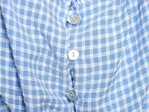 Détail de tissu vichy bleu et blanc avec trois boutons perlés sur un haut court
