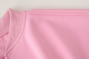 Detailed macro view of pink bomber jacket ribbed neckline and reinforced shoulder stitching