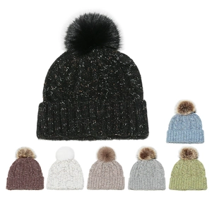 Detail of multi-color knit beanies with fluffy faux fur pom-poms in various winter tones