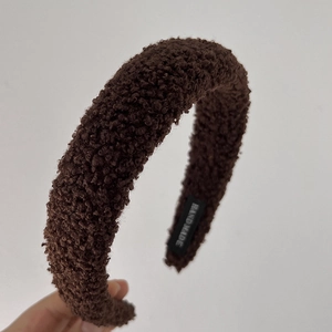Detail van bruine lamswollen hoofdband met een geweven HAND MADE label voor de winter