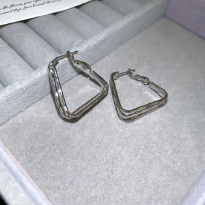 Detailed macro view of silver geometric hoop earrings placed in a velvet jewelry box