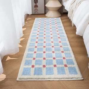 Blue and white checkerboard plush bath mat with pink dots on a wooden bedroom floor