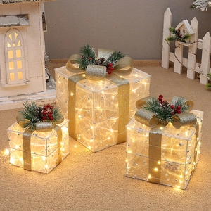 Close-up of white flocked Christmas gift box set with warm LED lights and golden bow