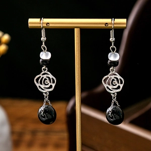 Detail of vintage flower earrings with black and white beads on a golden jewelry stand